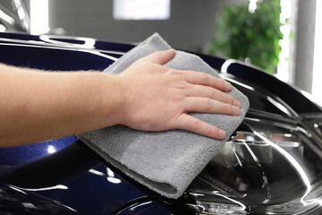 Service worker polishing car with microfiber cloth. Detailing a car - a man holds a soft microfiber in his hand and polishes the body. 