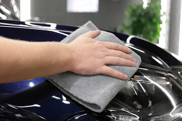 Service worker polishing car with microfiber cloth. Detailing a car - a man holds a soft microfiber in his hand and polishes the body. 