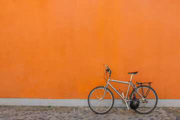 Black bicycle parked next to concrete orange wall. Banner, copy space. High quality photo
