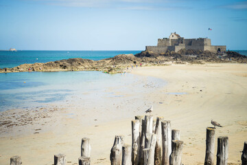 Saint Malo, view of Grand Bé Fort island from l'Eventail beach on a sunny day with low tide.  - obrazy, fototapety, plakaty