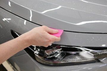 A car wrapping specialist applies a polyurethane film to the car. Selective focus. PPF protective film against chips and scratches. Car wrapping. 