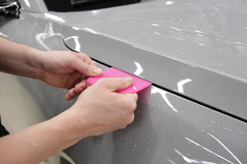 A car wrapping specialist applies a polyurethane film to the car. Selective focus. PPF protective...