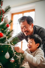 Chinese American grandfather decorating Christmas tree with his grandson