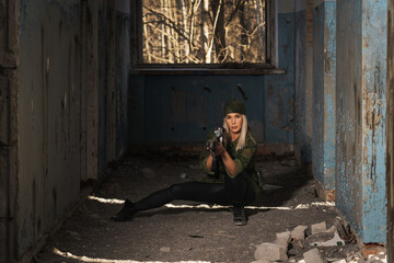 Beautiful young girl sniper at war in a destroyed building.