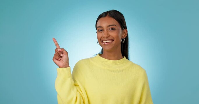 Face, woman and advertising presentation in studio of deal, information and choice on blue background. Happy portrait, indian model and pointing to mockup space, announcement and launch of promotion