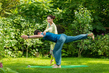 yoga teacher with student against nature background. woman trainer helps a man to perform yoga poses correctly, do yoga