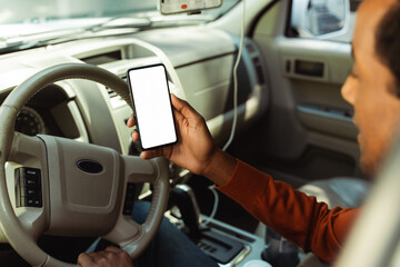 Young African American man holding mobile phone with blank white screen, mockup, place for text, sitting in car. Technology concept