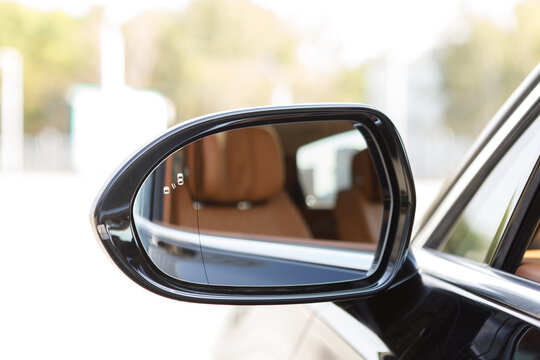 left rear view mirror in a luxury car with a reflection of a brown leather interior