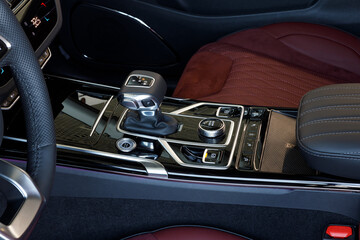 Selector automatic transmission with leather in the interior of a modern expensive car. Black and red leather car interior. Luxurious car instrument cluster. Close up shot