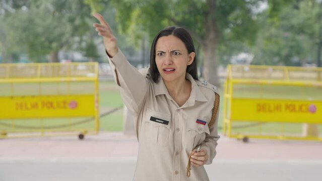 Angry Indian female police officer using whistle to call someone