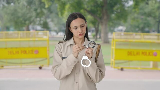 Indian female police officer inspecting handcuffs