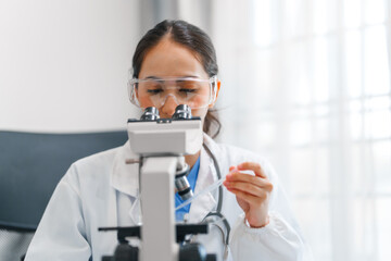 Young scientists pioneering medical discoveries in lab, with one scientist employing microscope for...