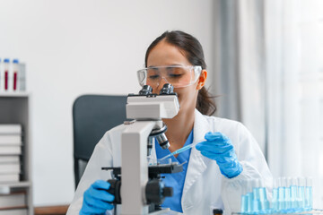 Young scientists pioneering medical discoveries in lab, with one scientist employing microscope for...