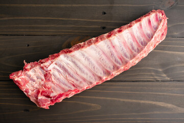 Raw Rack of Baby Back Ribs Underside on a Wooden Table: An uncooked rack of pork loin ribs viewed from directly above © Candice Bell