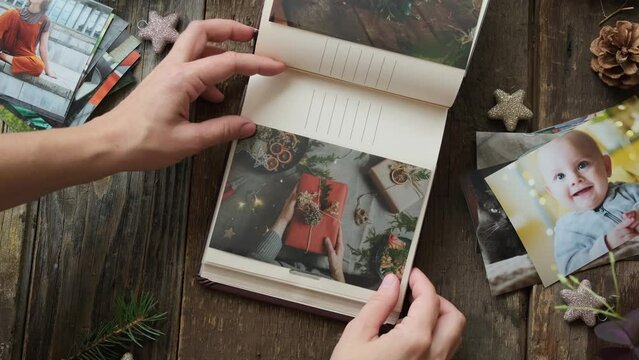 Photo printing, Christmas memories. Hands place printed photos into family picture album.