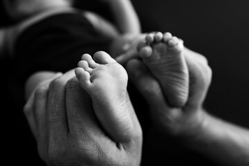 Black white shade beautiful shape hands of mother, hold tiny newborn baby feet on black background
