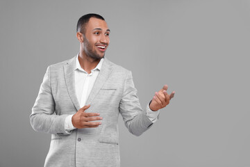 Young businessman in formal outfit on grey background. Space for text