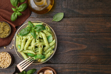 Delicious pasta with pesto sauce and ingredients on wooden table, flat lay. Space for text