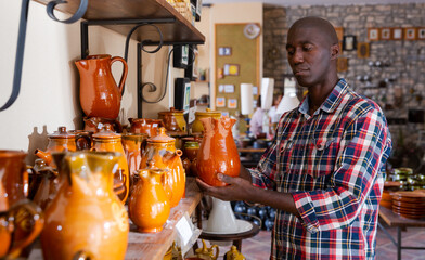 Young African man visiting ceramics studio in search of handmade pottery