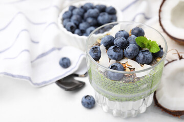 Tasty chia matcha pudding with coconut and blueberries on white table, space for text. Healthy breakfast