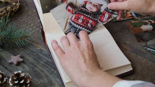 Photo printing, Christmas family memories. Hands put Christmas family photos into photo album.