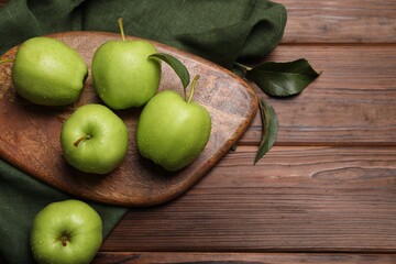 Ripe green apples with leaves and water drops on wooden table, flat lay. Space for text