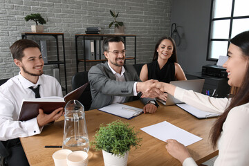 Human resources manager shaking hands with female applicant in office