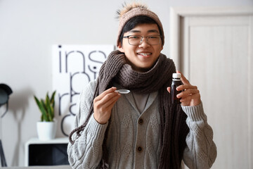 Ill Asian man with cough syrup at home