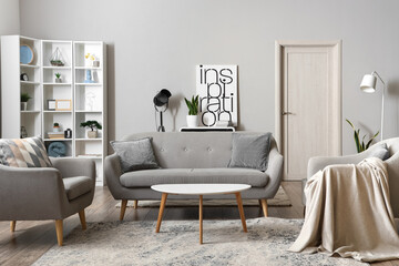 Interior of light living room with sofa, armchairs and coffee table