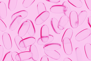 Translucent fish oil pills on pink background. Illustration of the concept of food nutrient, vitamins and supplements