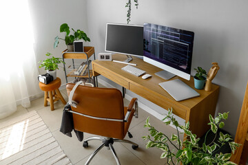 Interior of light office with programmer's workplace and houseplants