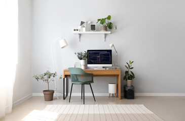 Interior of light office with programmer's workplace, shelf and houseplants