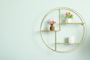 Stylish modern shelf with different home decor on pale green wall