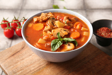Bowl of tasty beef stew on grey tile background