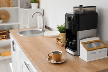 Modern coffee machine with cup of espresso on wooden counter in kitchen