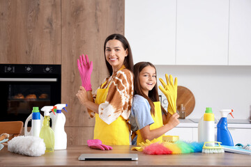 Happy mother with her little daughter putting rubber gloves for cleaning in kitchen