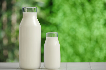 Bottles of fresh milk on white tile table outdoors