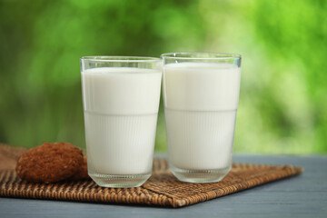 Glasses of fresh milk and sweet cookies on grey wooden table outdoors
