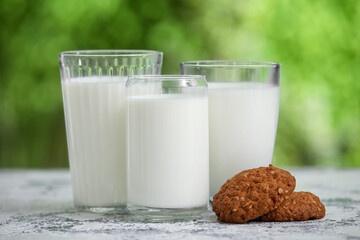Glasses of fresh milk and sweet cookies on grunge table outdoors