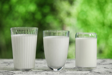 Glasses of fresh milk on grunge table outdoors
