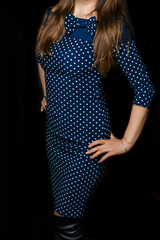 Female skinny figure brunette with long hair in a blue tight-fitting dress with a polka dot pattern...
