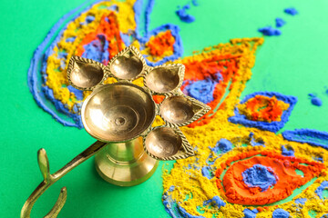 Composition with diya lamp and colorful powder for celebration of Divaly on green background