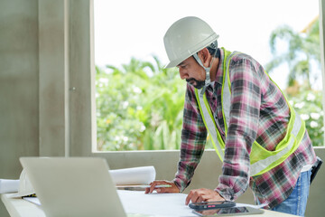 Indian man Wear green reflective vest and safety helmet in houses under construction. Indian...