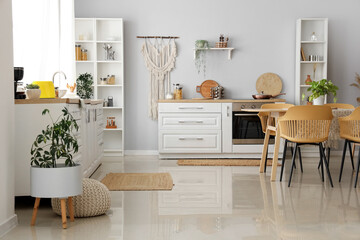 Interior of light kitchen with white counters and wicker carpets