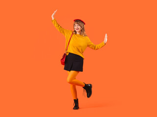 Fototapeta na wymiar Stylish young woman in fall clothes on orange background