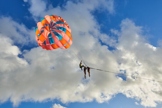 Phuket - Patong beach - August 28, 2023: Thai man taking off with parasail at sunset on Patong beach in Phuket, Thailand