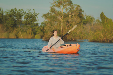 asian younger woman kayaking in fresh water lagoon at rayong province eastern of thailand