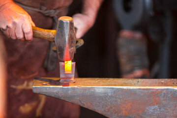 Blacksmith forging metal with tools