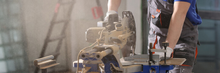 Worker cuts wooden board with circular saw close-up.