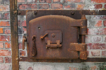old rusty oven door surrounded by bricks in an abandoned factory